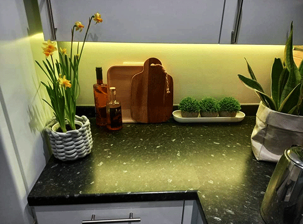 Yellow lighting within kitchen cabinet LED corner profile combined with RGBW seamless LED tape strip.
