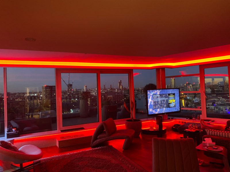 Red illuminated curved cove within London cityscape view apartment
